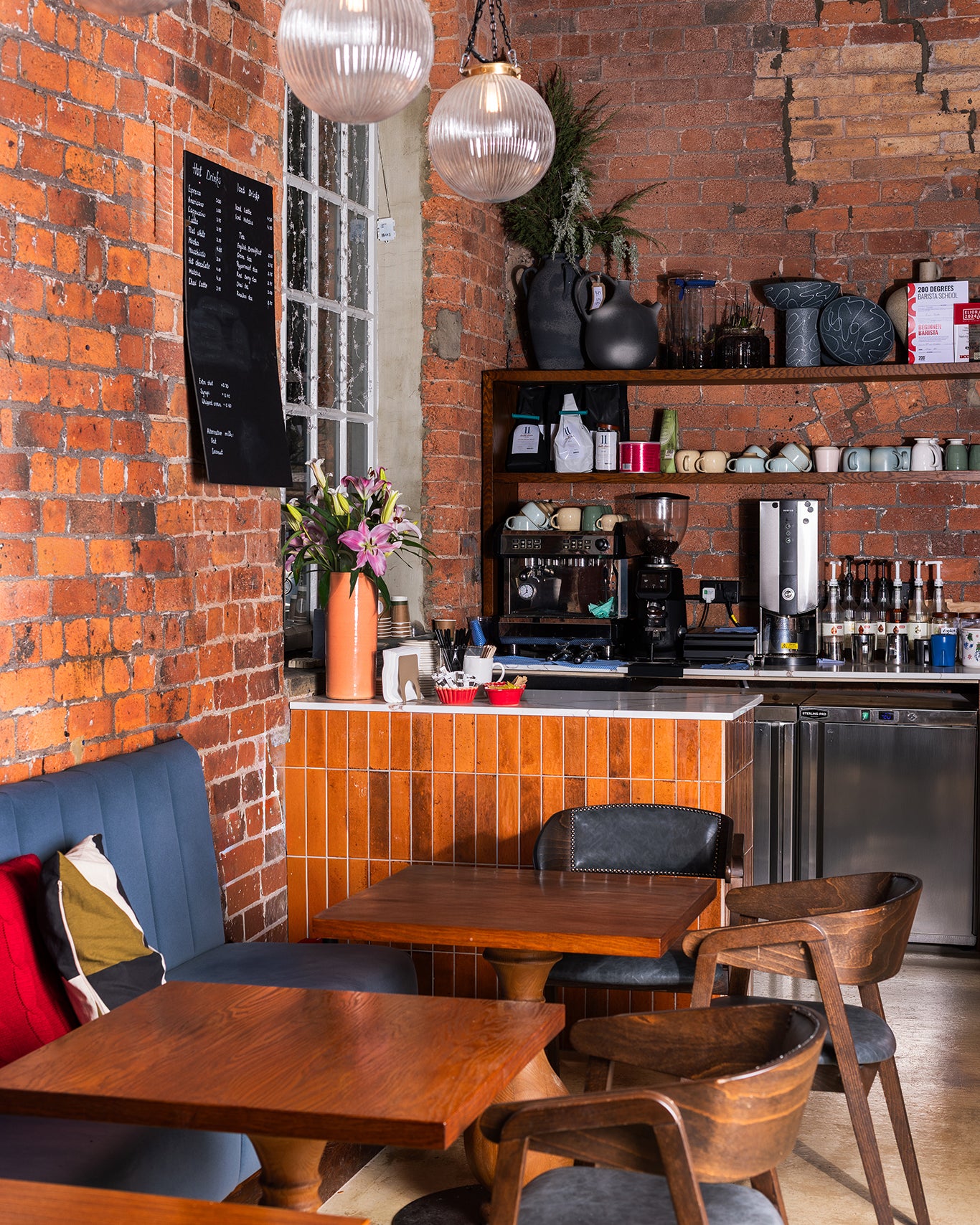 Coffee shop interior with brick walls, wooden tables, and chairs.