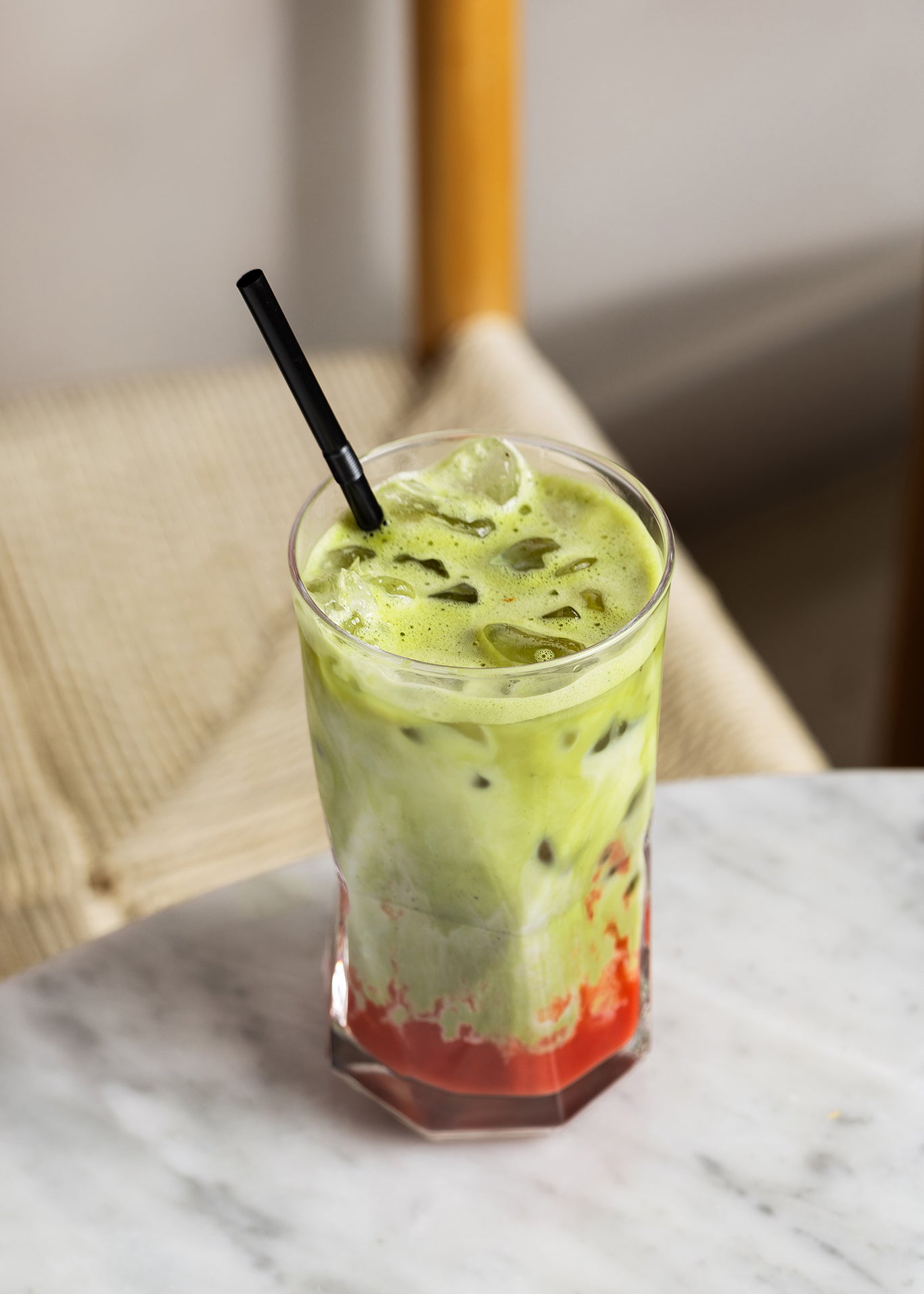 A glass with iced strawberry matcha latte on a marble surface